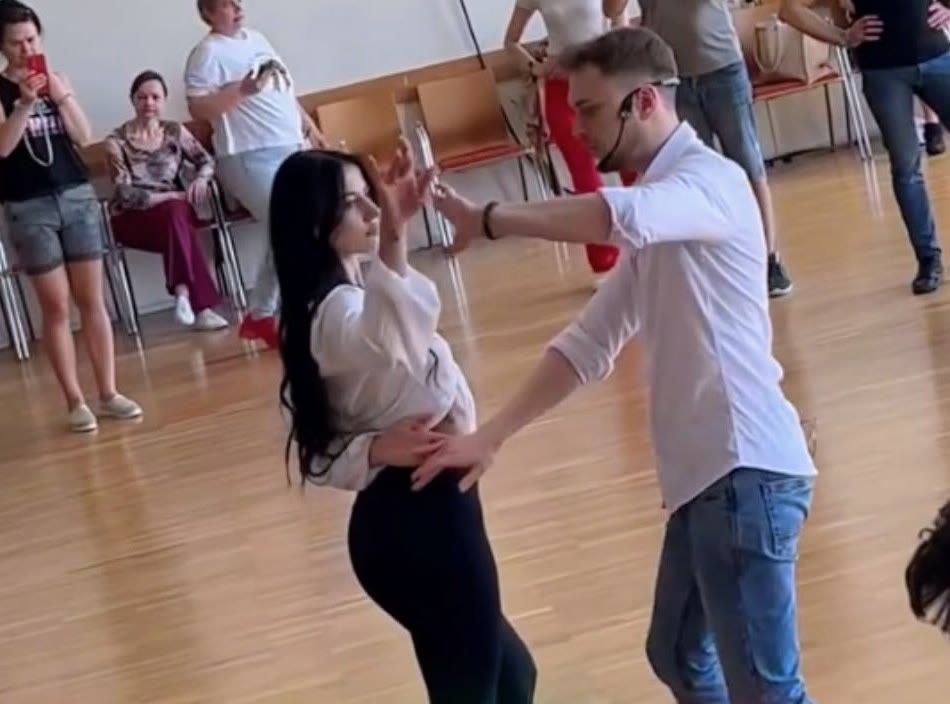 Bachata Utena mokytojas su partnere rodo žingsnius, grupė stebi salėje